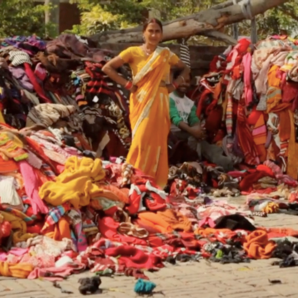 A woman stands before a pile of clothes, highlighting the importance of sustainable yarns from recycled materials.