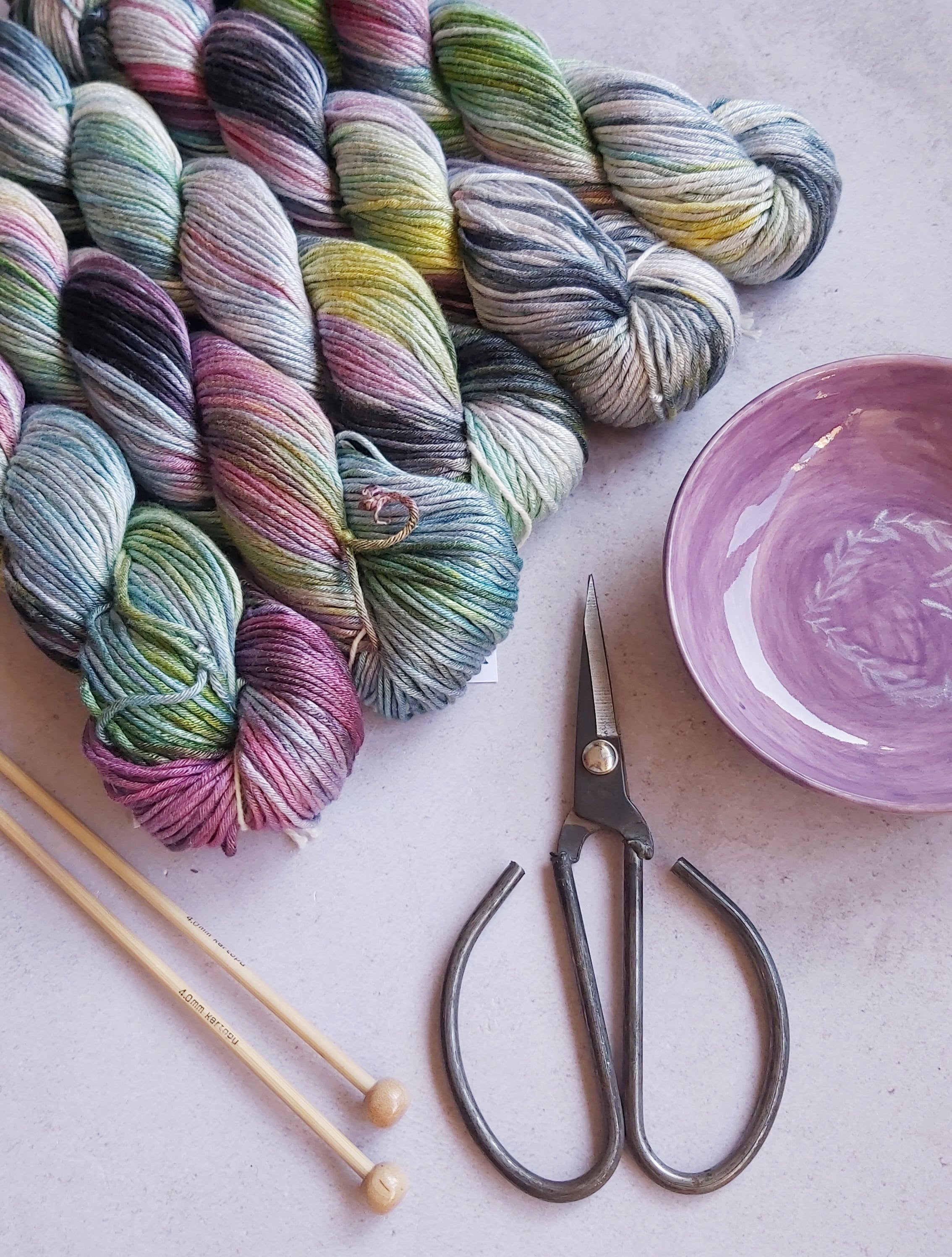 Knitting essentials: vibrant yarn, wooden needles, and sharp scissors, ready for a creative project