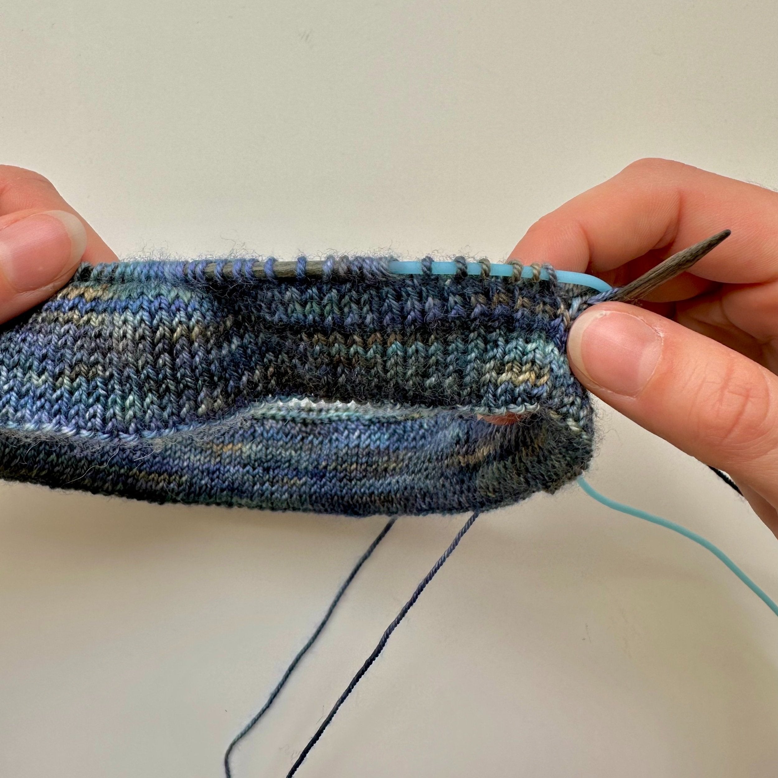 A person knitting with a silicone keeper cord assisting in the process