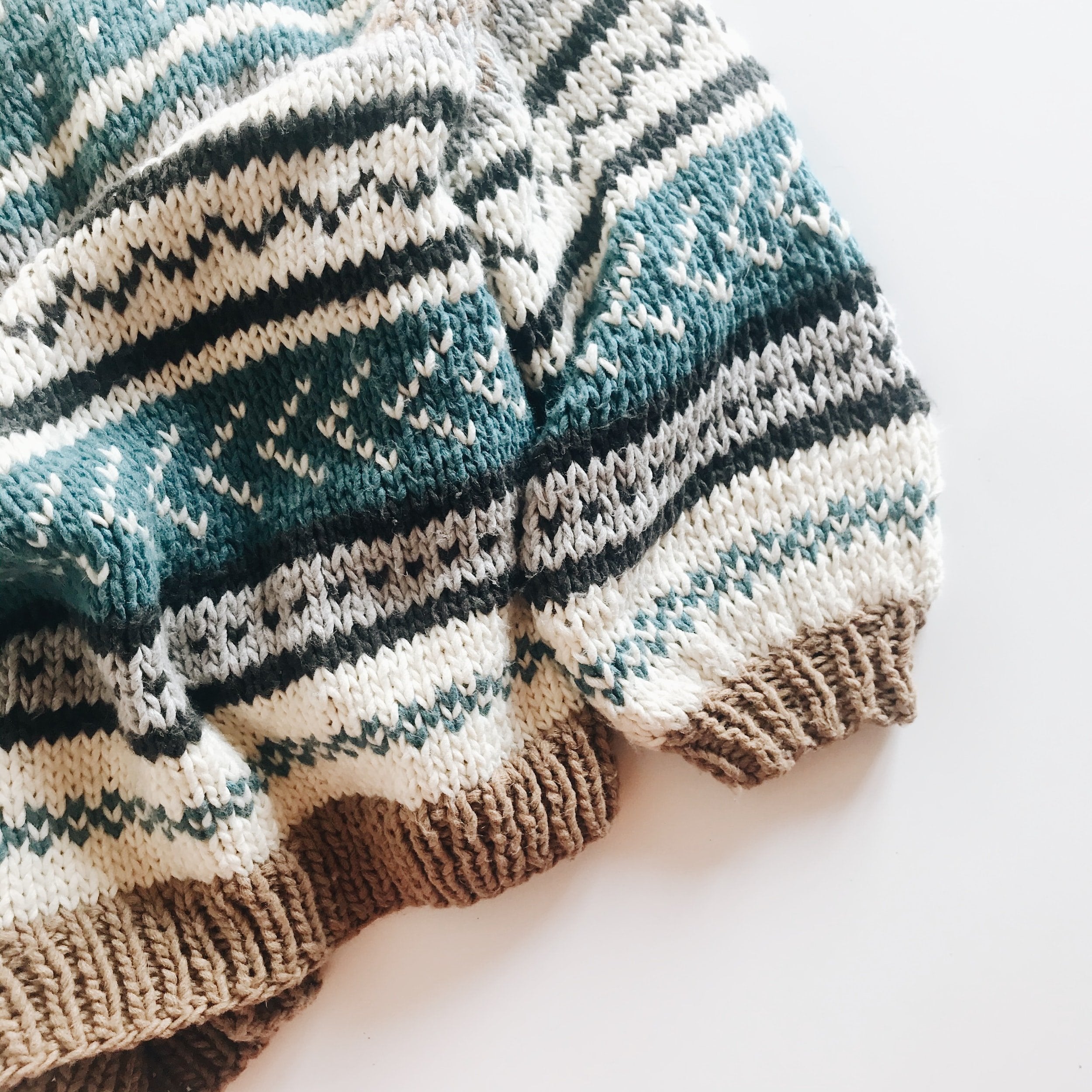 Hand-knit wool sweater showcasing a beautiful design of blue, brown and white stripes.