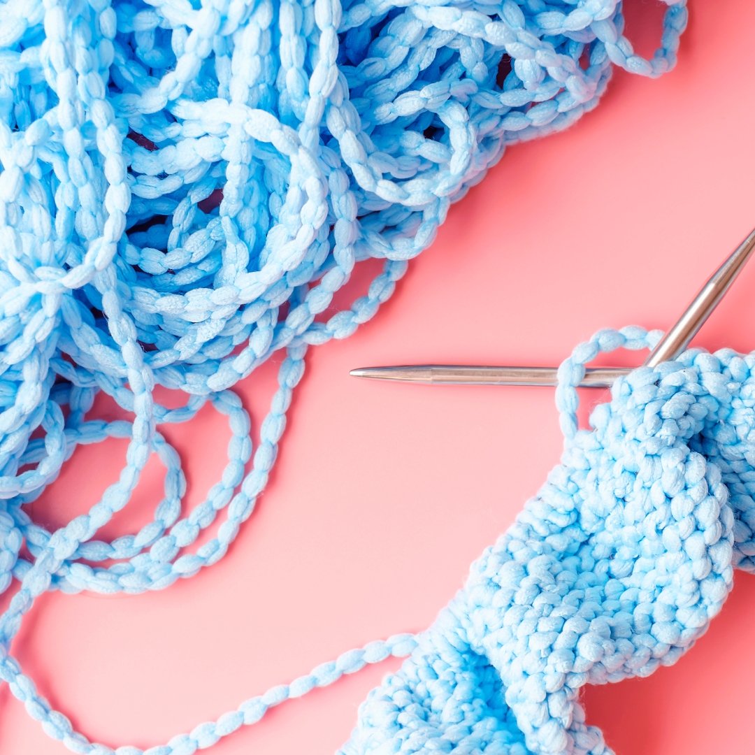 Knitting project in progress with blue yarn and needles.