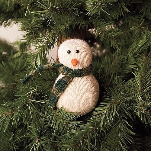 Hand-knitted Mini Snowman Christmas ornament sitting on a Christmas Tree