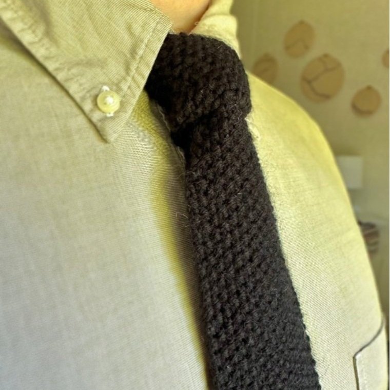 A man wearing a dark colored knitted tie