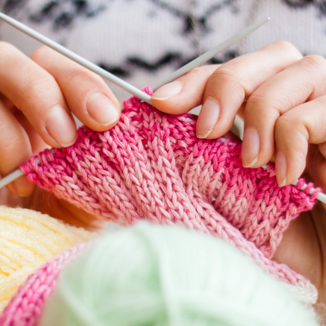 close up of someone knitting a pink gradient project