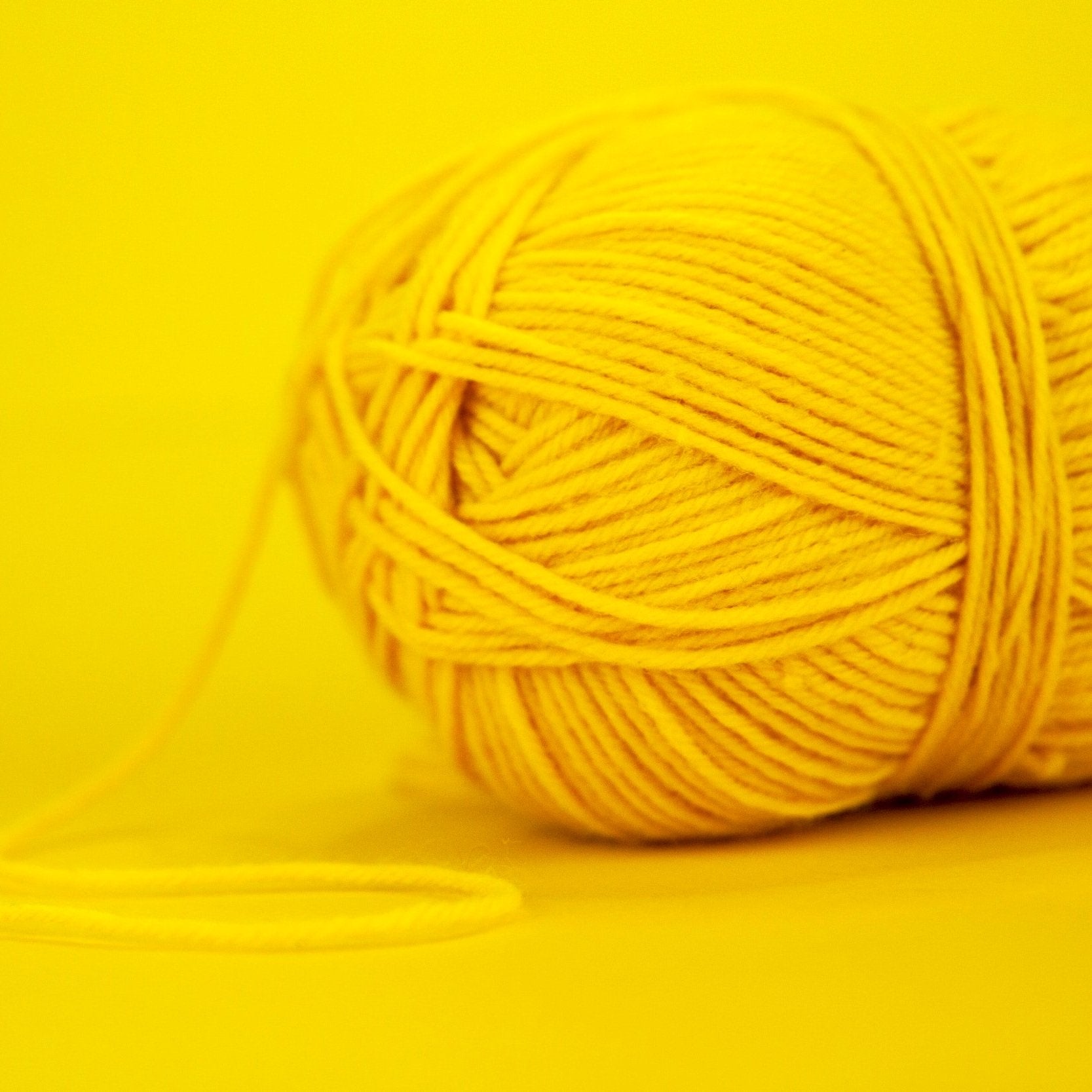 A display of vibrant yellow acrylic yarn on a yellow background