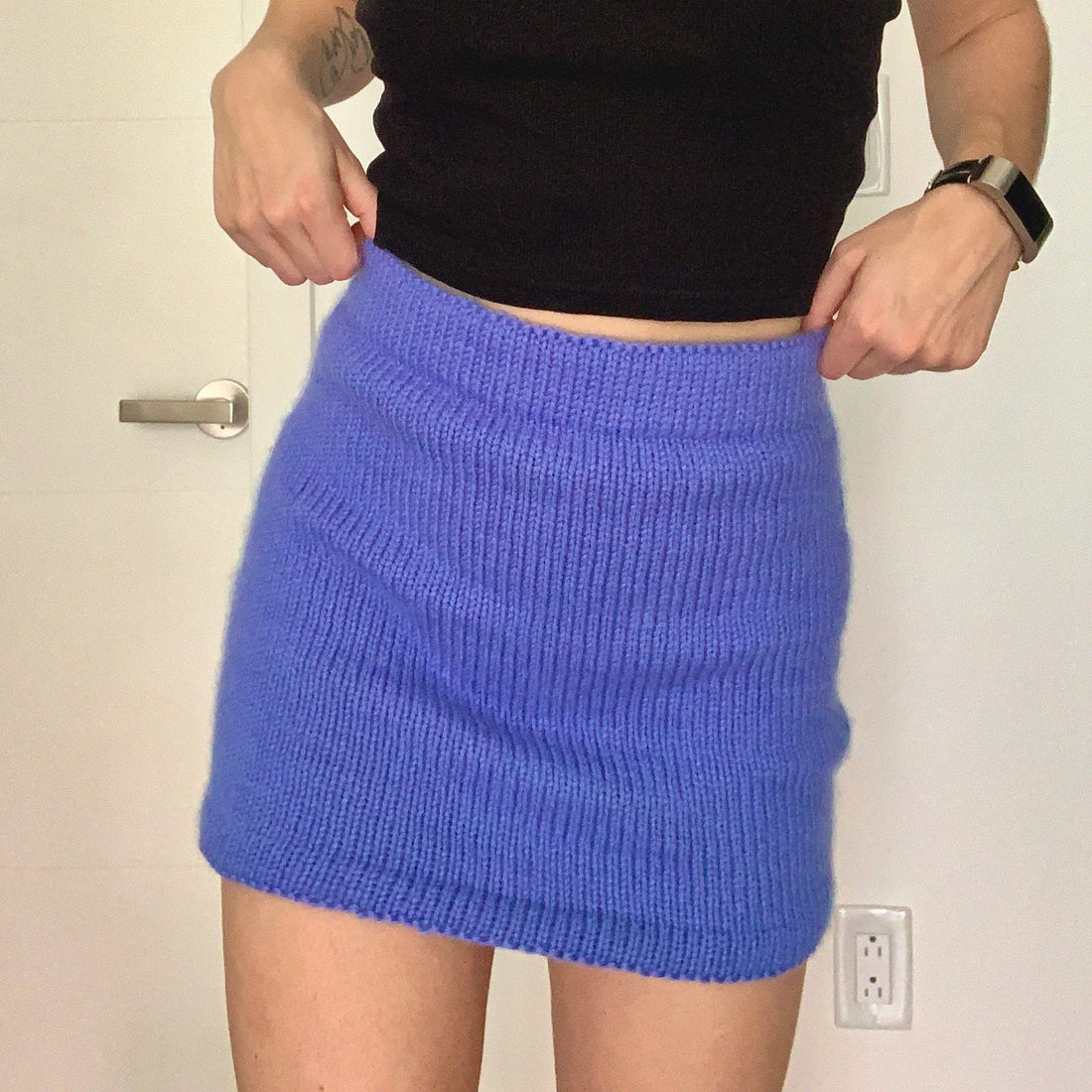 A woman models a custom blue knitted skirt, showcasing a unique made-to-measure design.