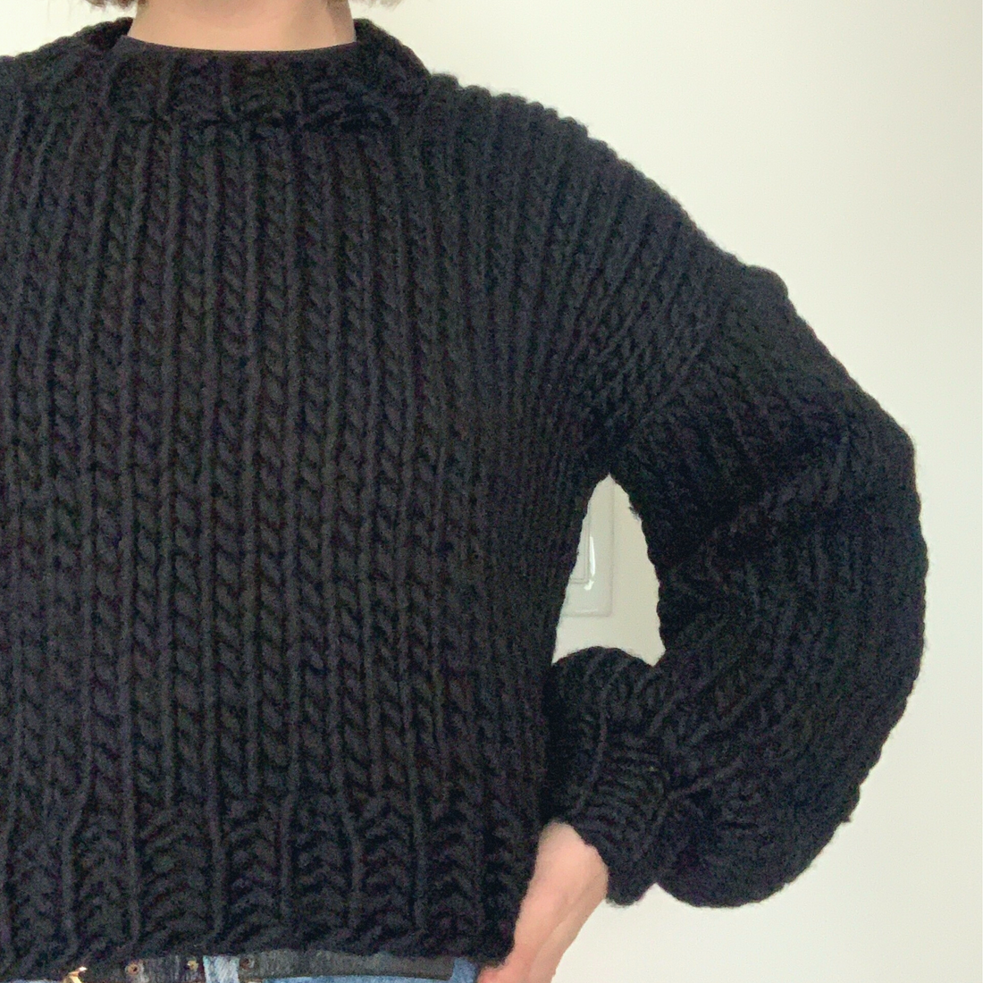 A woman wearing a black bulky knitted sweater in pristine condition showcasing proper care for knits