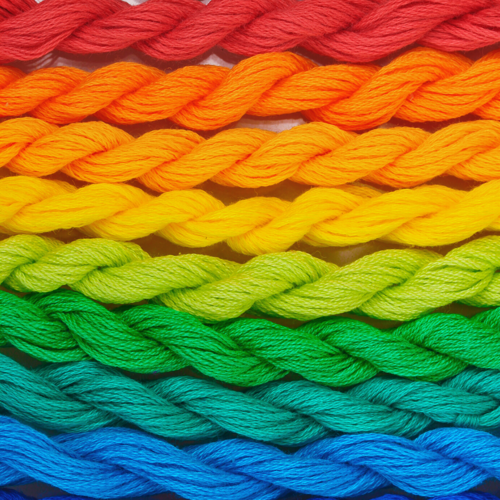A rainbow of threads represents the inclusive spirit of queer knitters in the fibers community.