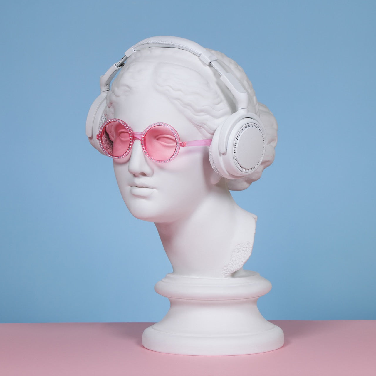 A white bust wearing pink glasses and headphones, representing a knitting podcast theme.