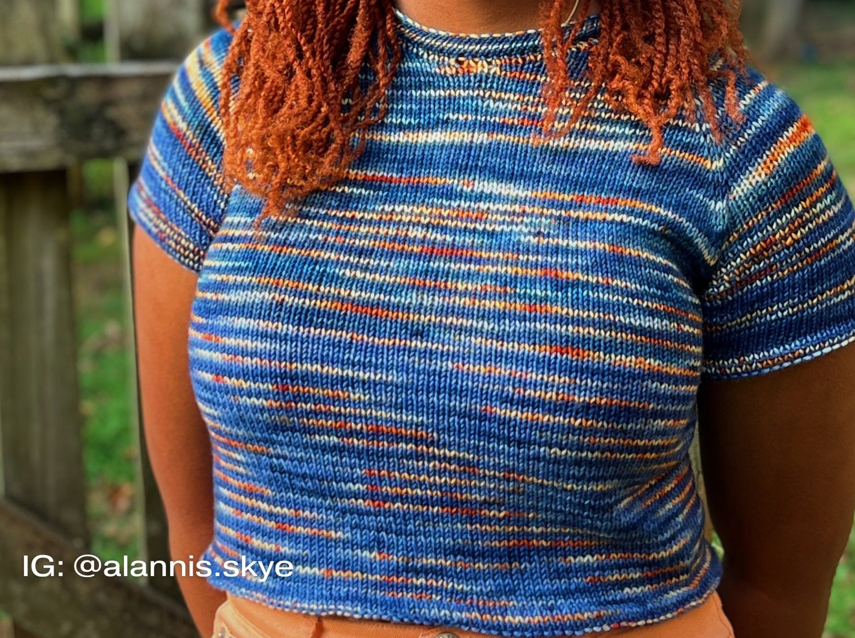 a woman in a striped knitted top highlighting The Staple Tee's unique design.
