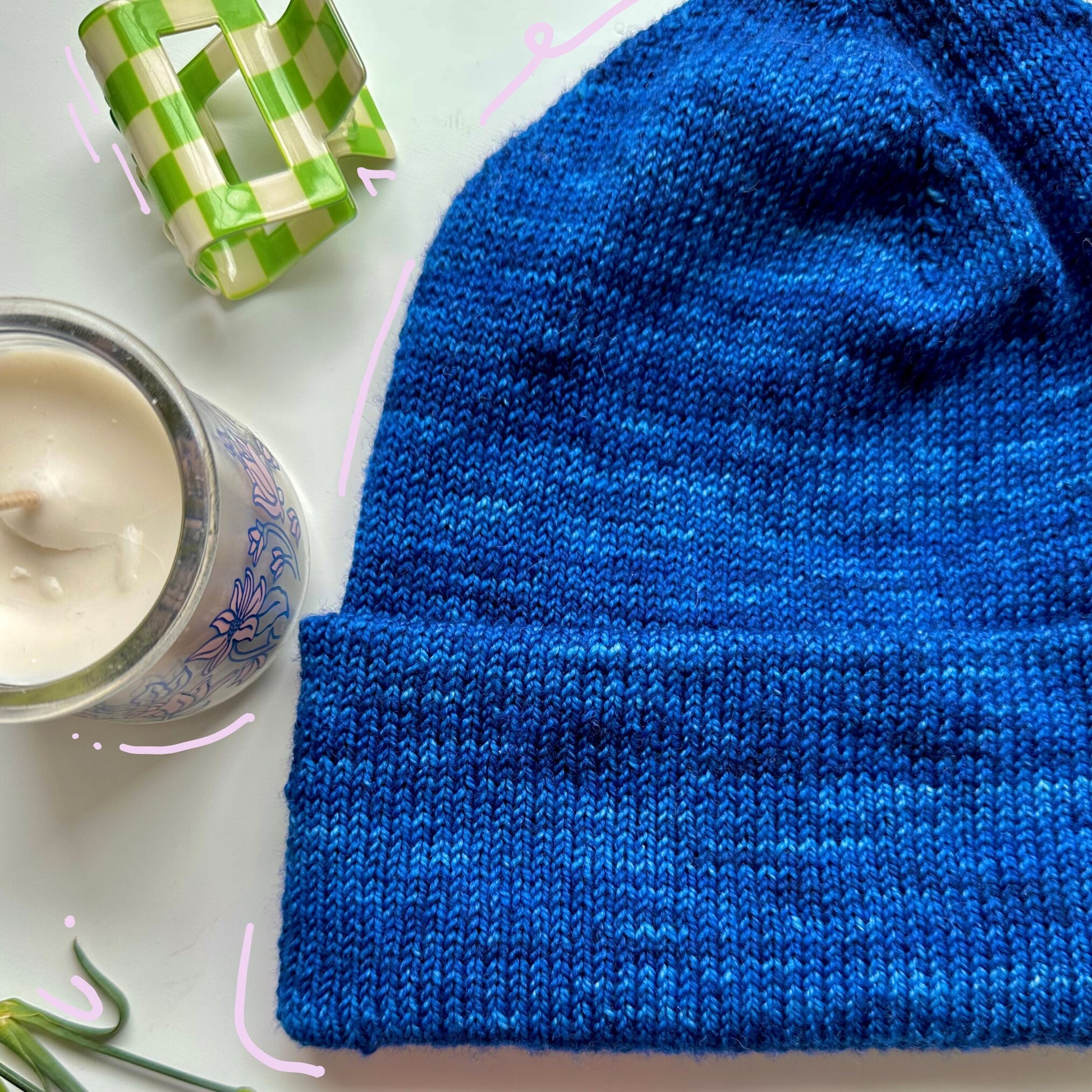 a lifestyle image of a blue knitted hat representing the unique design of the Tall Staple Beanie PDF pattern.